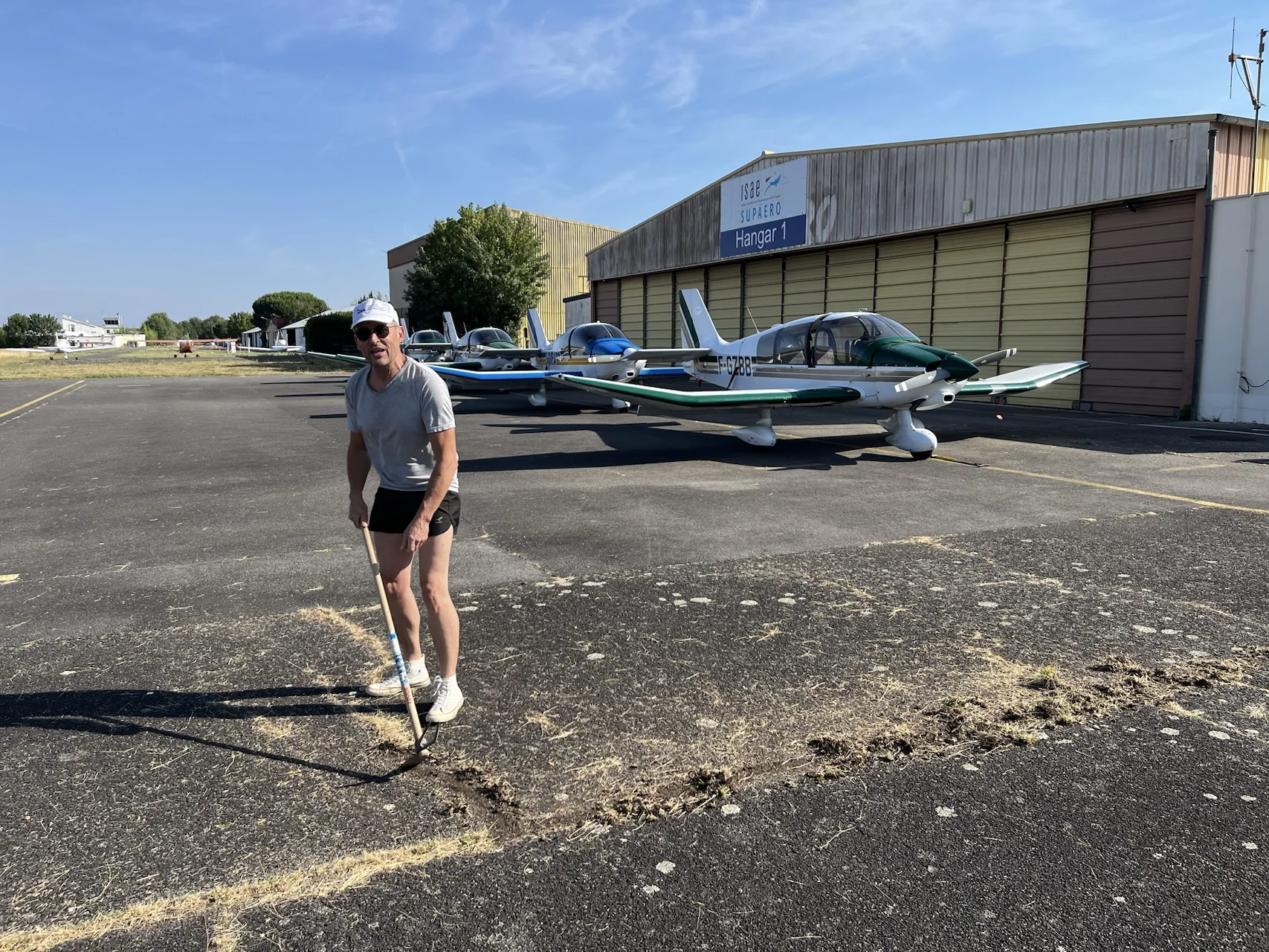 Un membre désherbe le parking devant les avions du club
